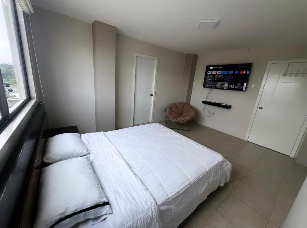 een slaapkamer met een wit bed en een raam bij CRUCITA BEACH KP in Crucita