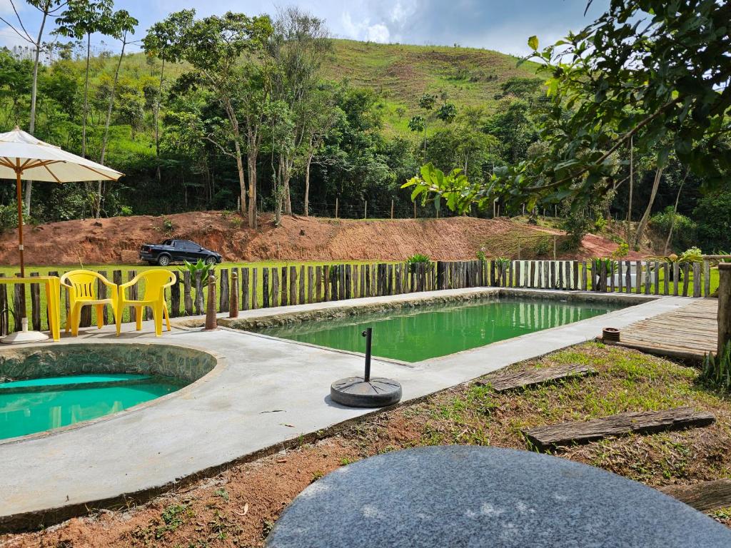 a pool with a table and chairs and an umbrella at Sitio Reis Membeca in Paraíba do Sul