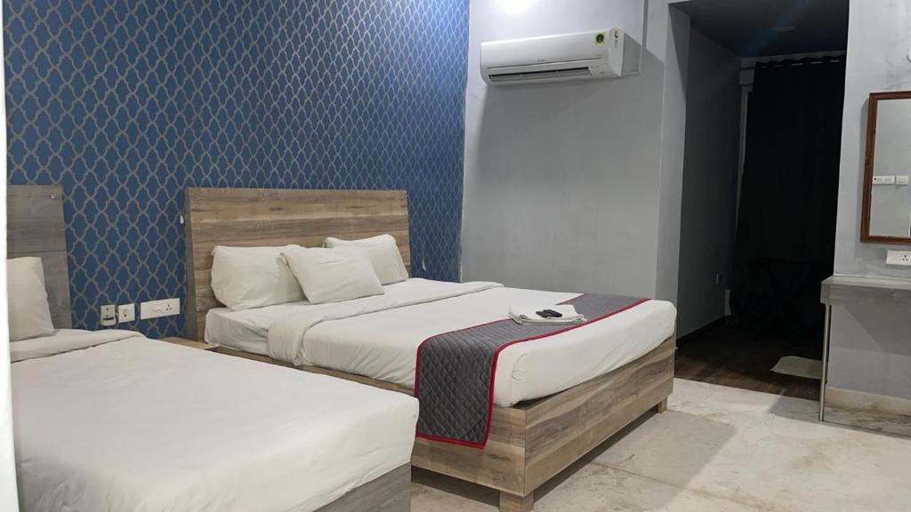 Duas camas num quarto com papel de parede azul em Stayz Inn Hotels - The Gate Way Of Madras - Near Chennai Central Railway Station em Chennai