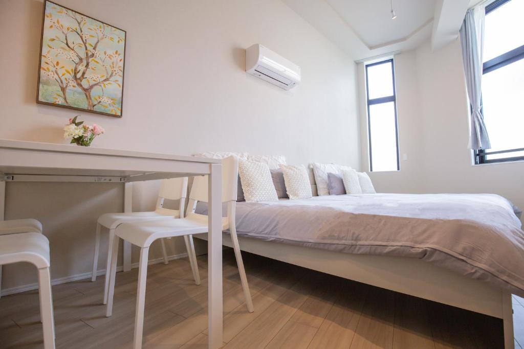 a white bedroom with a bed and a table at The most comfortable and best choice for accommodation in Yoyogi SioY5 in Tokyo