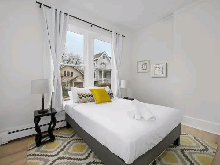 a white bedroom with a large bed with a yellow pillow at King's Palace in Lodwar