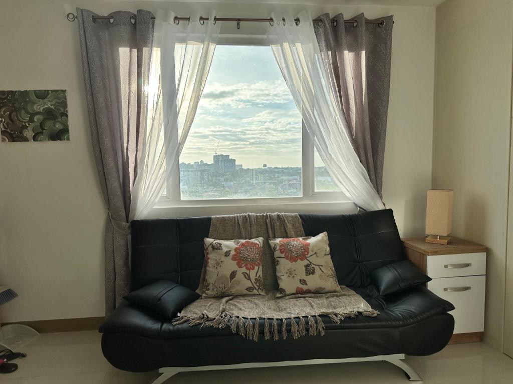 a black leather couch sitting in front of a window at Bright & Breezy 2 BR Unit with Balcony in Manila