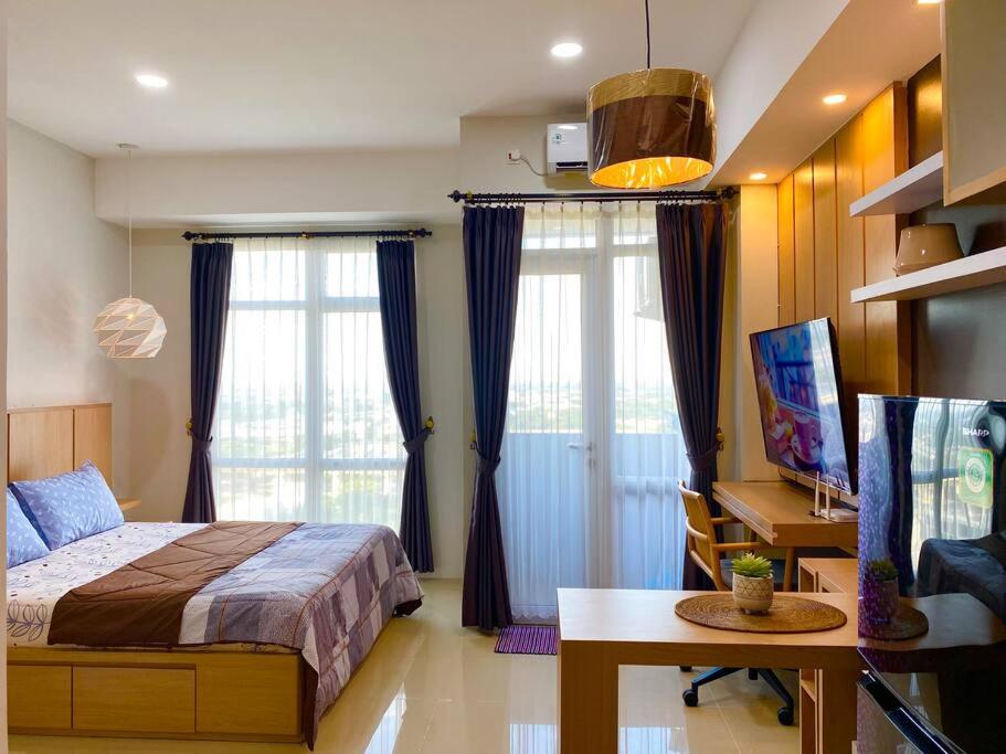 a bedroom with a bed and a desk and windows at Apt Vasanta Innopark Studio S1oN with Pool in Jarakasta