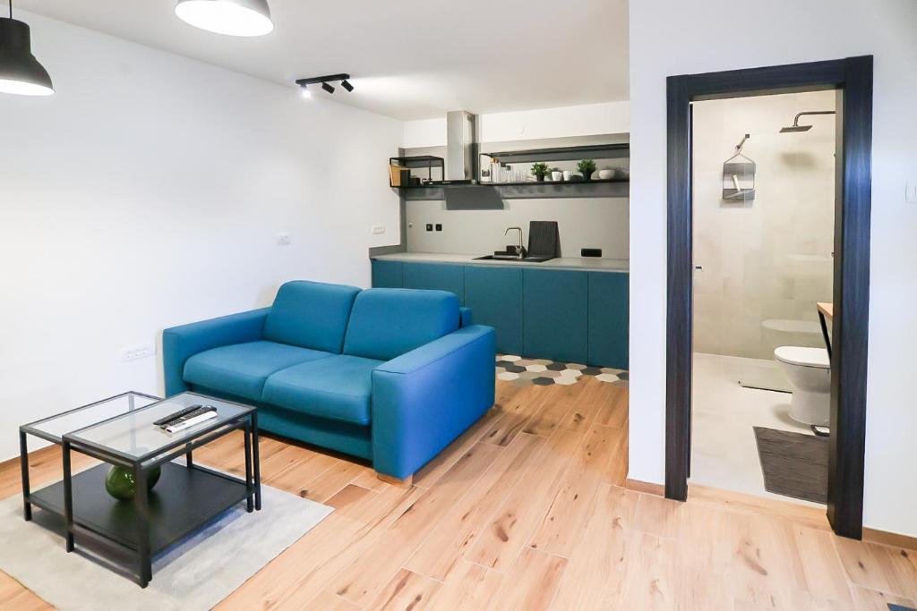 uma sala de estar com um sofá azul e uma mesa em Apartmani Jana em Osijek