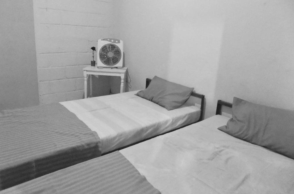 Kos Omah Yanto 19 في جاكرتا: سريرين في غرفة بها مروحة