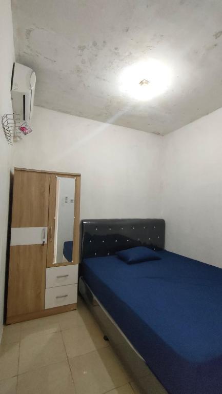 een slaapkamer met een blauw bed en een spiegel bij Almalik Kost in Serang