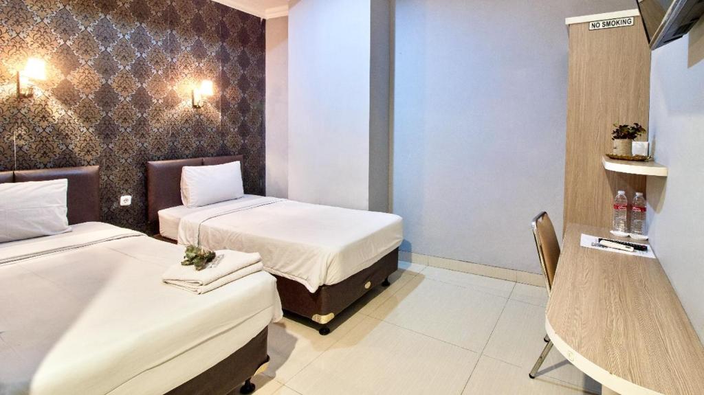 ein Hotelzimmer mit 2 Betten und einem Stuhl in der Unterkunft FLAMENCO URBAN STAY in Jakarta