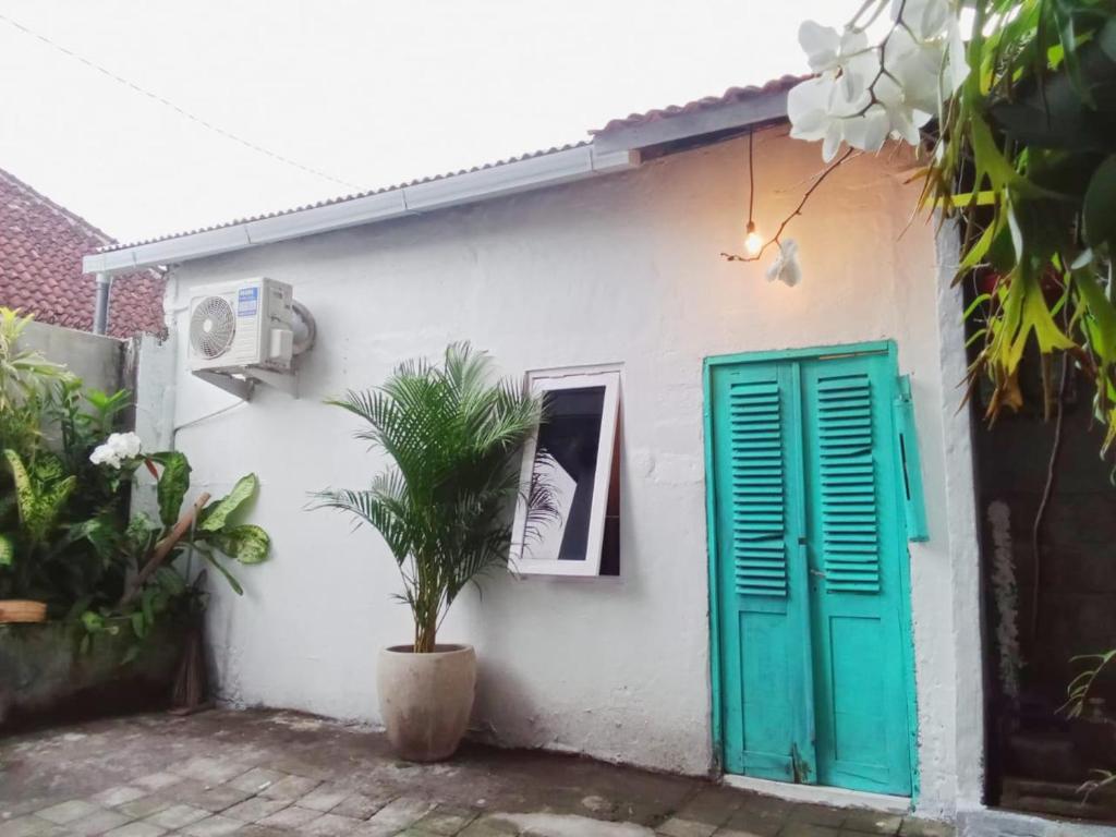 una casa bianca con una porta verde e una pianta di Local House Grenceng 2 a Denpasar