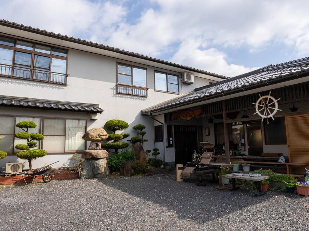 ein weißes Gebäude mit einem Rad an der Seite in der Unterkunft Guest House Nakamura in Ama