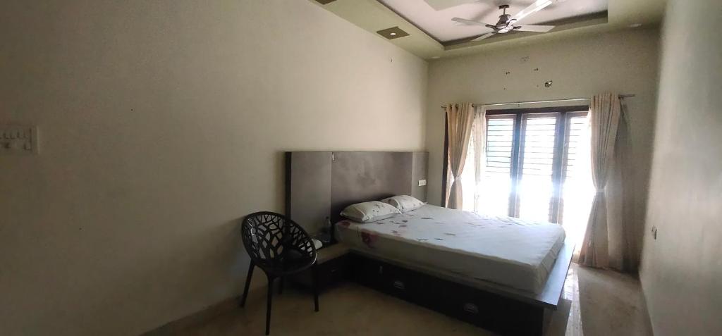 a bedroom with a bed and a chair and a window at SHAN Stay home Mysore No in Mysore
