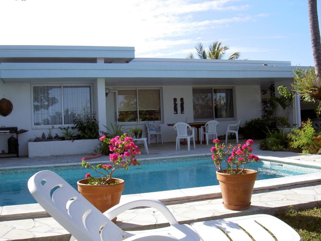 a house with a swimming pool with chairs and flowers at villa utrillo in Noumea