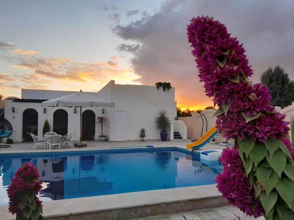a villa with a swimming pool and a sunset at Encanto getaway in Sheikh Zayed