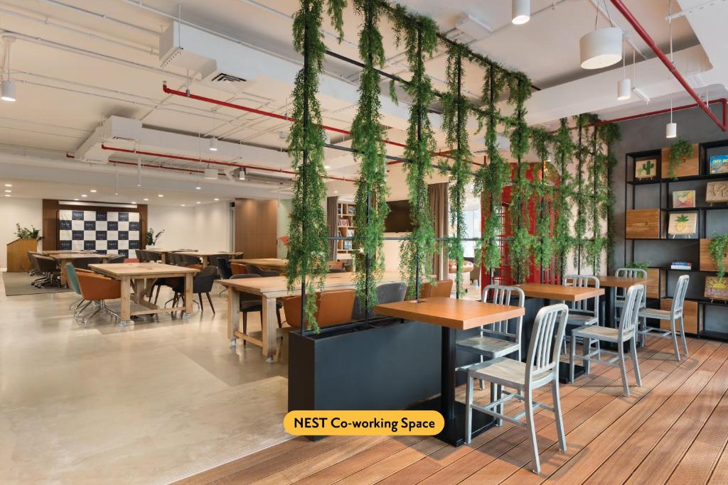 a restaurant with wooden tables and plants hanging from the ceiling at TRYP by Wyndham Dubai in Dubai