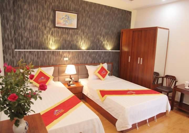 a hotel room with two beds and a vase of flowers at Khách sạn Bảo Sơn 1 in Lao Cai