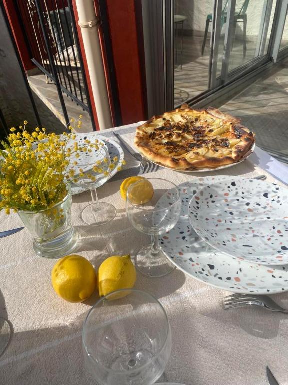 a table with two pizzas and lemons on it at MAISON PLEIN SUD SUR LES TOITS au 2 terrasses in Montagnac