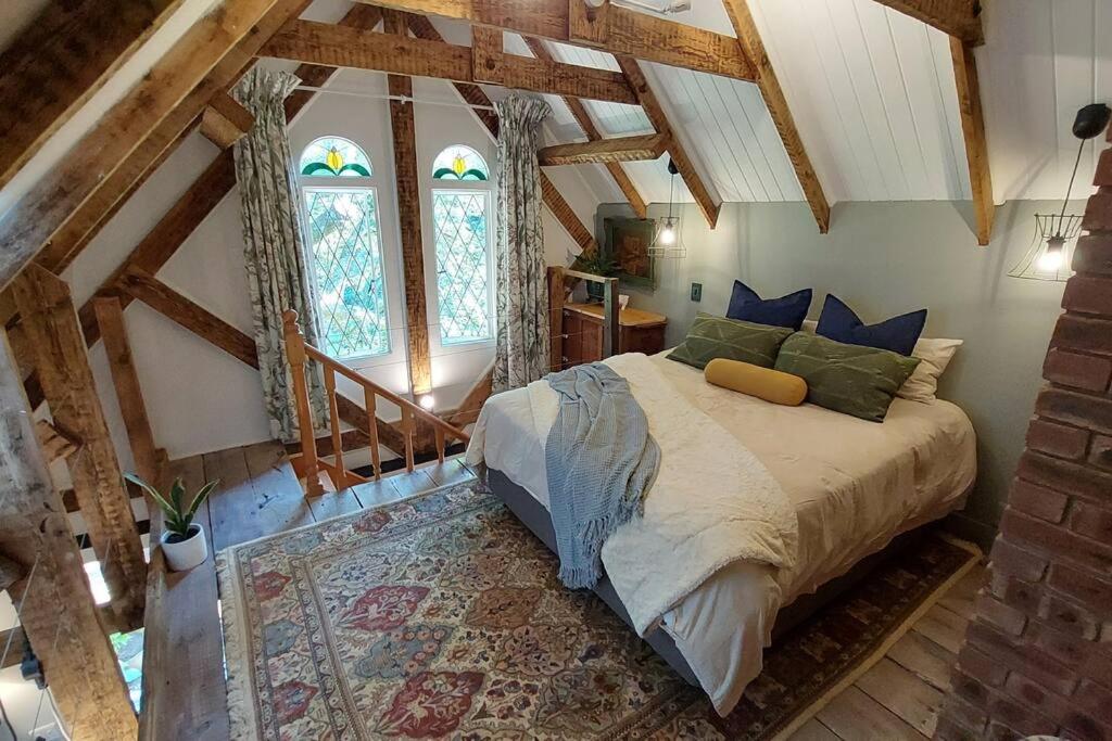 a bedroom with a bed and two windows at Lacebark Cottage in Hilton