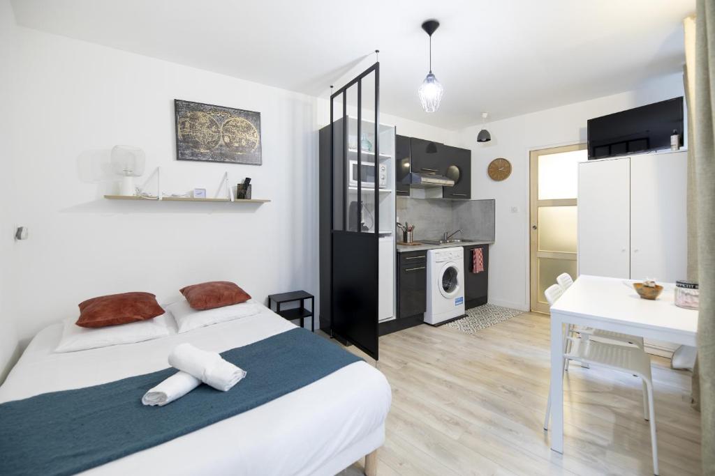 a bedroom with a white bed and a kitchen at Le petit MIAMI in Thionville