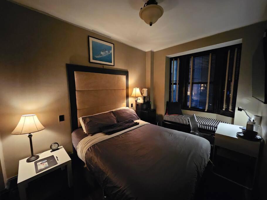 a bedroom with a bed and two lamps and a window at Hotel-Studio* @ The Mansfield Midtown in New York