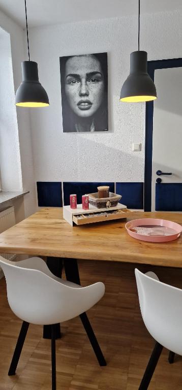 einen Esstisch mit zwei weißen Stühlen und zwei Leuchten in der Unterkunft Bahnhof City Loft & Apartments in Augsburg