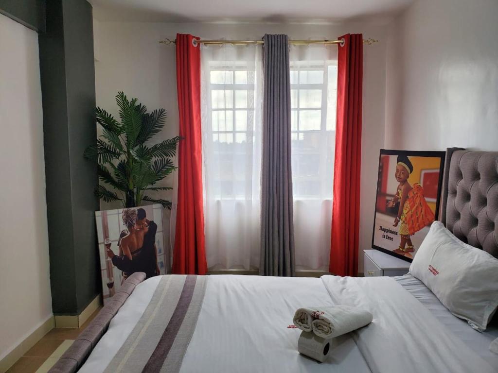 um quarto com uma cama grande e cortinas vermelhas em macdade apartment em Nairobi