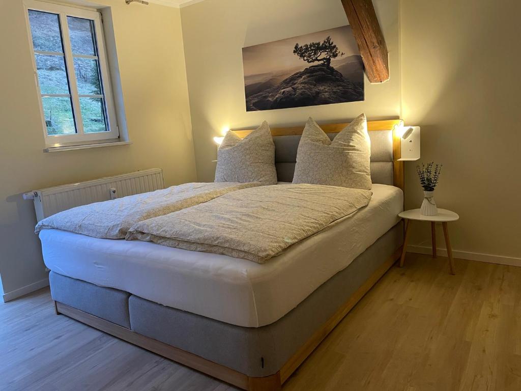 een slaapkamer met een groot bed met witte lakens en kussens bij Ferienwohnung Kohlbornsteinblick am Malerweg in Krippen