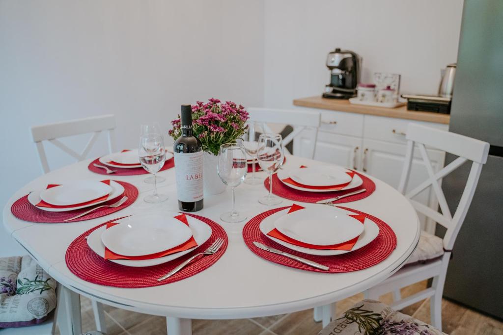 a white table with red and white plates and wine glasses at Bella's Sea apartment-Beach, Sea garden ,Old Town, Free Parking, Free EVcharging Station in Varna City