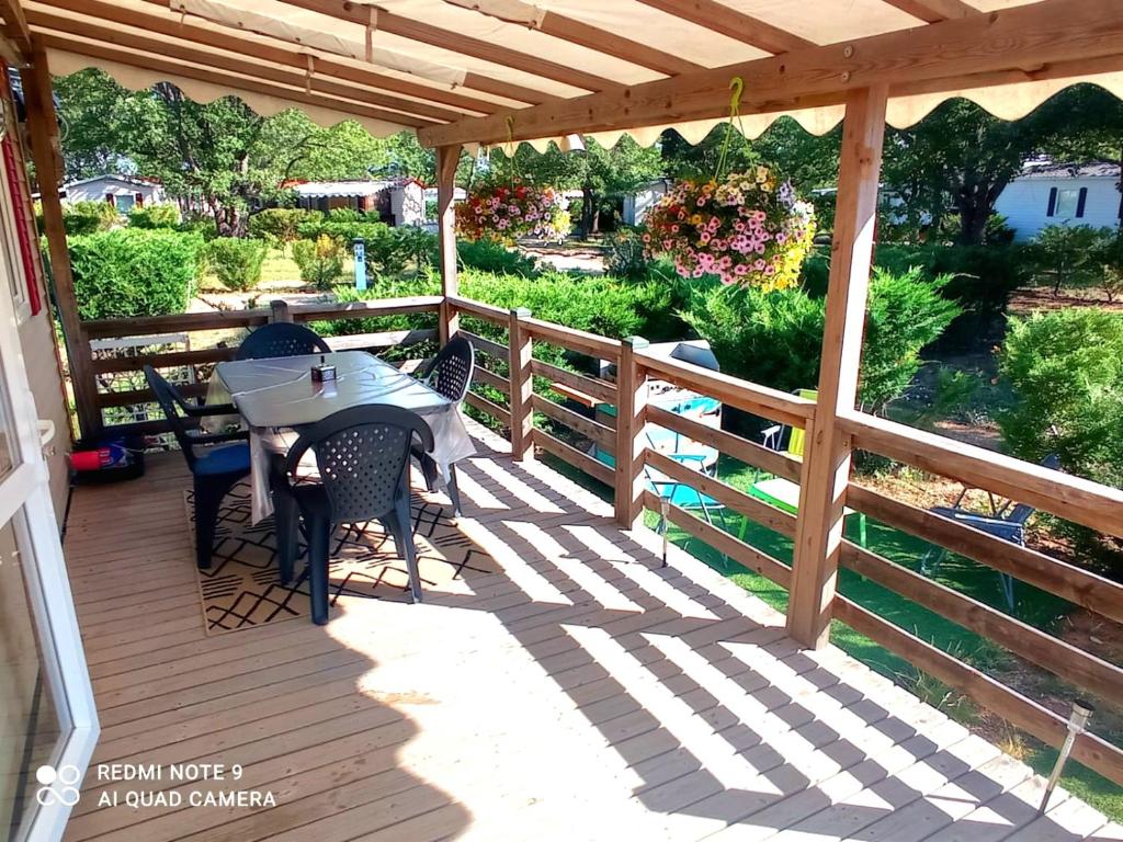 une terrasse en bois avec une table et des chaises dessus dans l'établissement CAMPING / LOCATION MOBIL HOME : Les gorges du Verdon et lac de Sainte Croix., à Sainte-Croix-de-Verdon