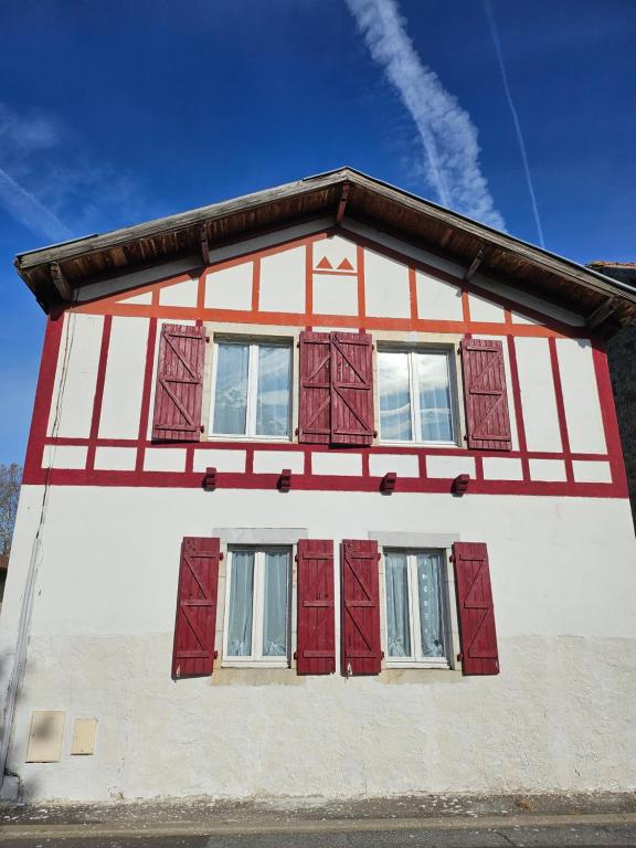 Casa roja y blanca con ventanas con persianas rojas en Chambres d hôtes Au Bonheur du Gave piscine et jacuzzi, en Lahontan