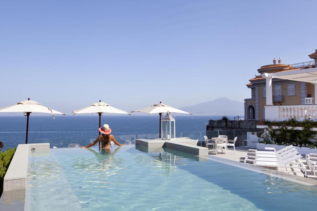 a woman in a swimming pool with a view of the ocean at Hotel Corallo Sorrento in Sant'Agnello