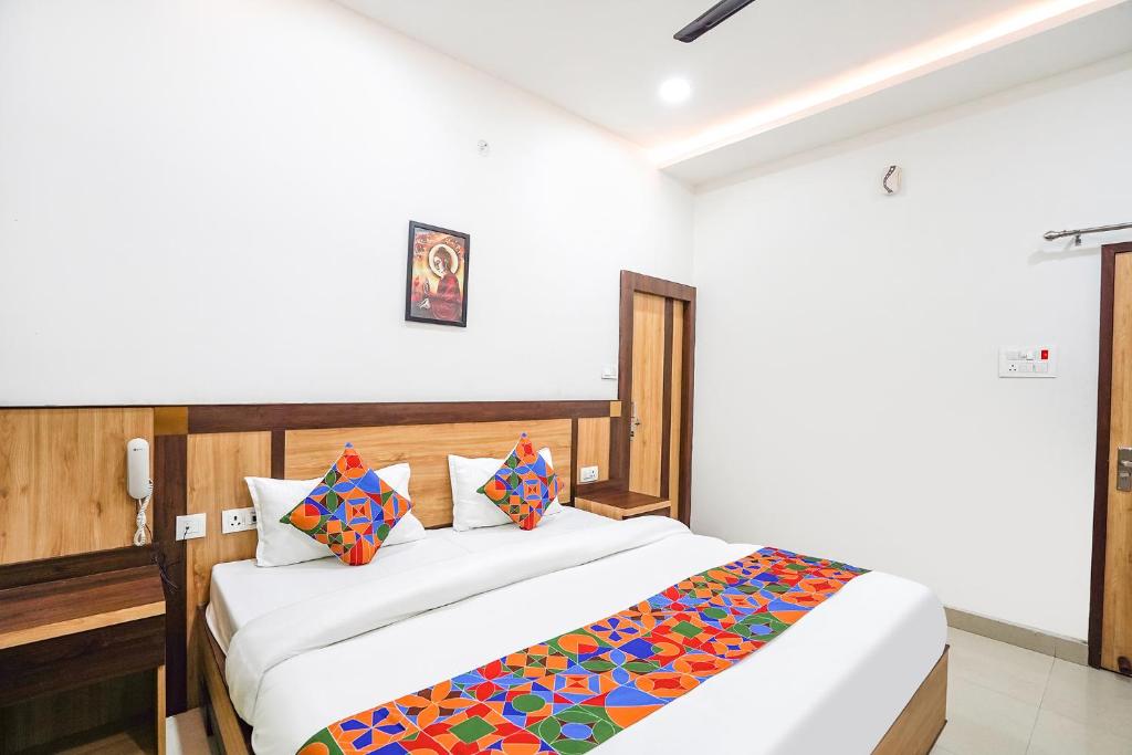 a bedroom with a large white bed with colorful pillows at FabHotel Vairagi inn in Varanasi