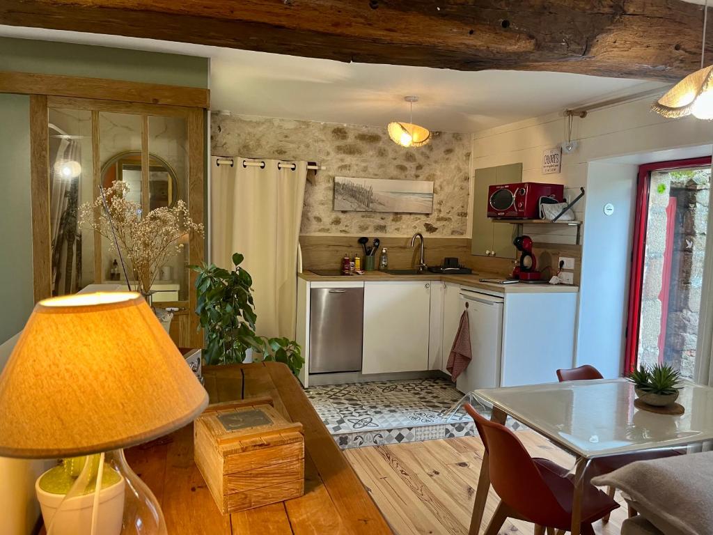 ein Wohnzimmer mit einem Tisch und einer Küche in der Unterkunft Maison à la campagne Les Oliviers in La Bruffière