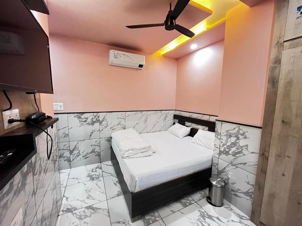 a small bedroom with a bed with a ceiling fan at SPOT ON YADAV GUEST HOUSE in Jaipur