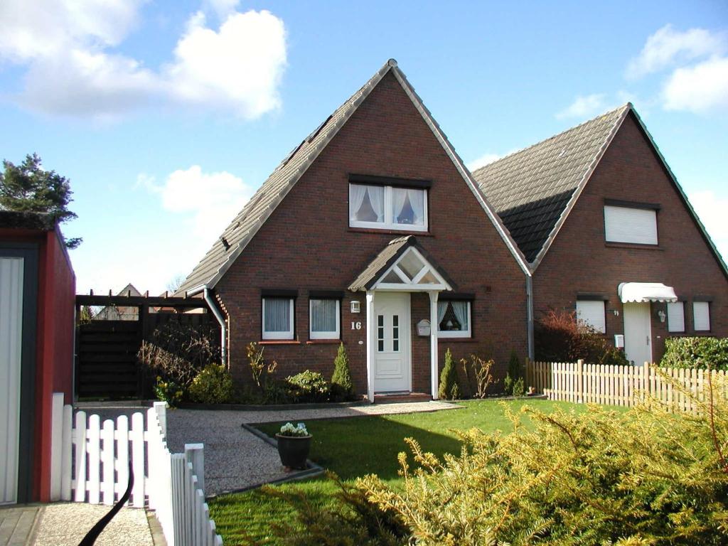 a red brick house with a white fence at Haus Wattkieker in Hooksiel