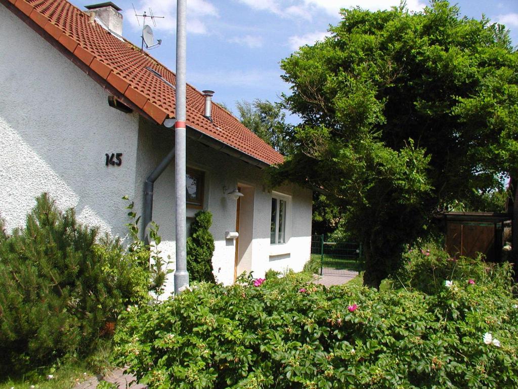 een wit huis met een rood dak en wat struiken bij Haus Deichblick 1 in Hooksiel