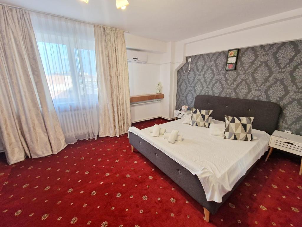 Cette chambre comprend un lit et une grande fenêtre. dans l'établissement BON TON Residence, à Drobeta-Turnu Severin