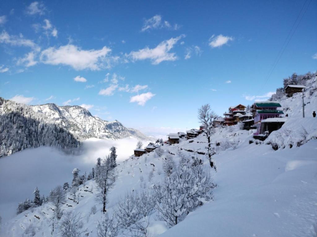 uma montanha coberta de neve com uma aldeia à distância em Kiran Home Stay em Shoja