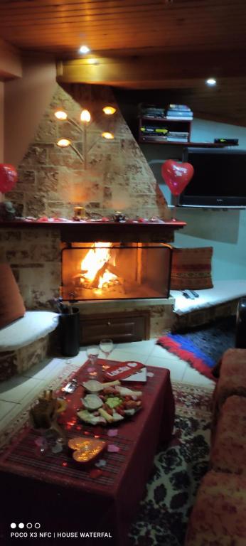 a living room with a fireplace and a table with food at Guest House Waterfall in Eptalofos