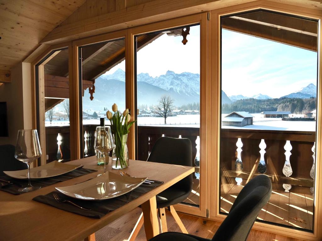 ein Esszimmer mit einem Tisch und einem großen Fenster in der Unterkunft Ferienwohnungen Alpinum in Krün