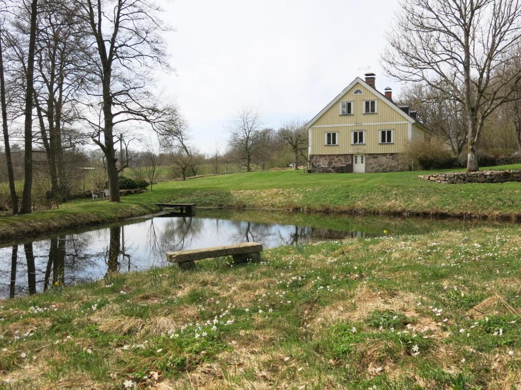une maison assise à côté d'une rivière avec un banc dans l'établissement Östra Nyrups Lantliv, à Höör
