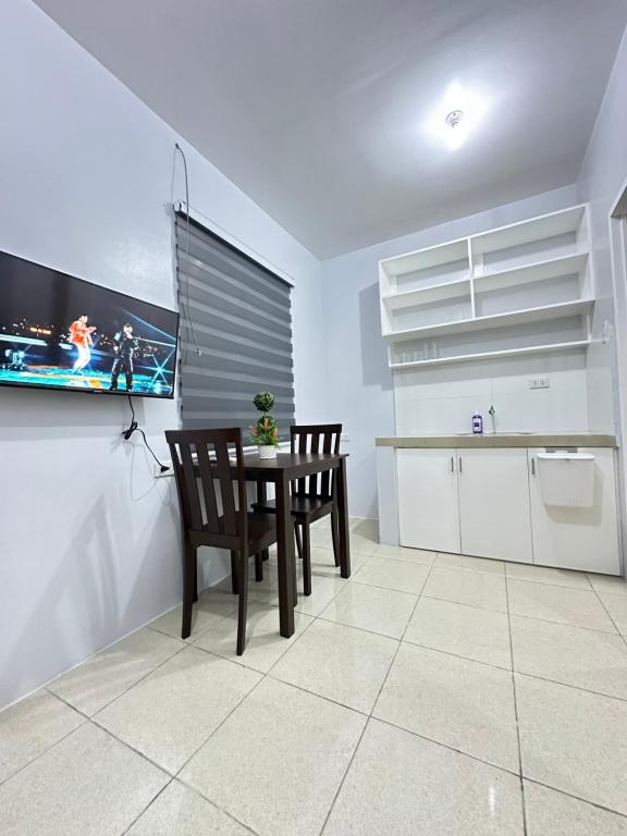 Il comprend une cuisine avec une table et deux chaises ainsi qu'une télévision. dans l'établissement DKAT Apartments, à Manille