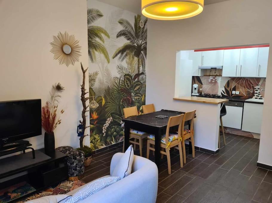 un salon avec un canapé et une table et une cuisine dans l'établissement L’Oasis Fleuri, à Bourg-de-Péage