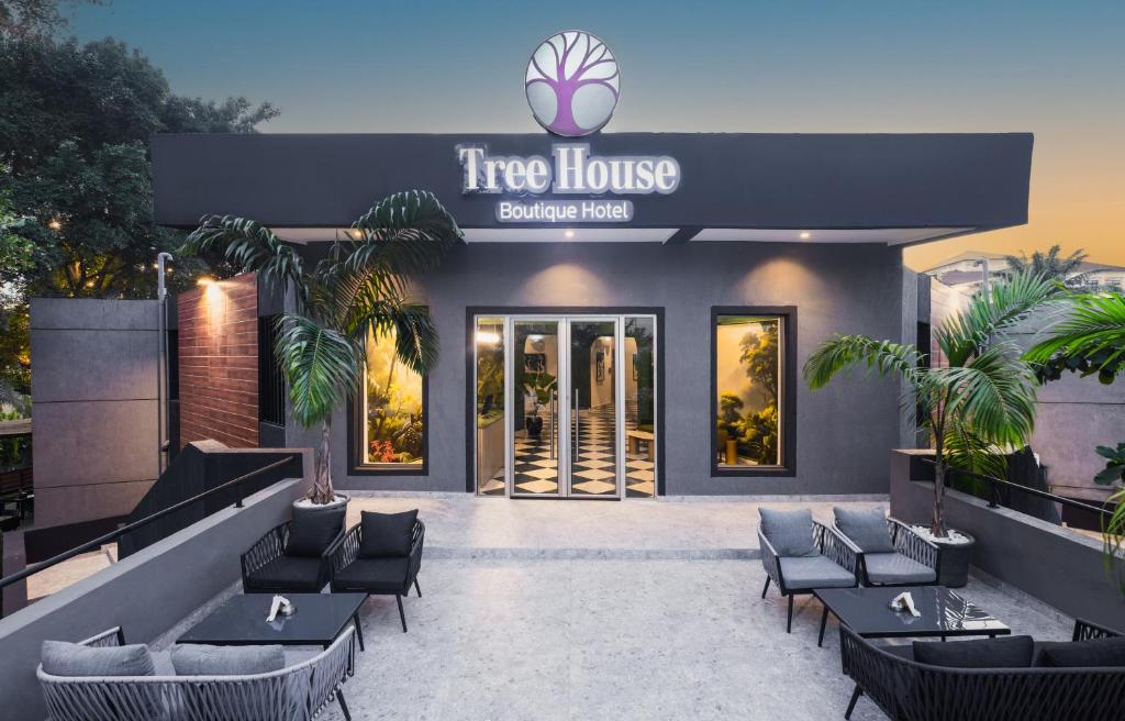 Tree House Boutique Hotel في أبوجا: تقديم مطعم منزل شجرة مع طاولات وكراسي