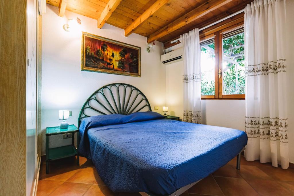 sypialnia z niebieskim łóżkiem i oknem w obiekcie Oasi del Relax w mieście Costa Rei