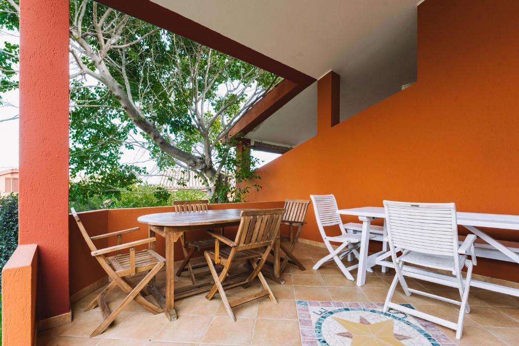patio ze stołem, krzesłami i drzewem w obiekcie Oasi del Relax w mieście Costa Rei