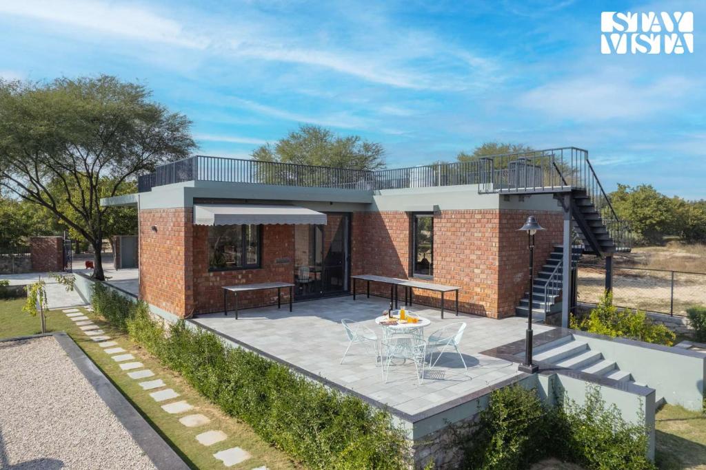 une maison en briques avec une terrasse et un patio dans l'établissement StayVista's Kachnaar Villa - Pet-Friendly Villa with Lawn, Terrace & Indoor-Outdoor Games, à Jaipur