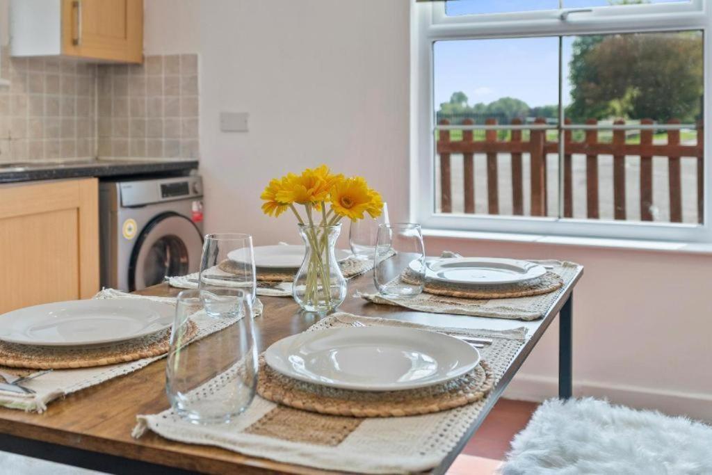 a table with plates and glasses on it in a kitchen at Tranquil Retreat in Heart of Somerset Countryside in Highbridge