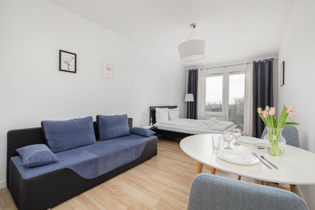 ein Wohnzimmer mit einem blauen Sofa und einem Tisch in der Unterkunft Potulicka Comfort Studio in Stettin