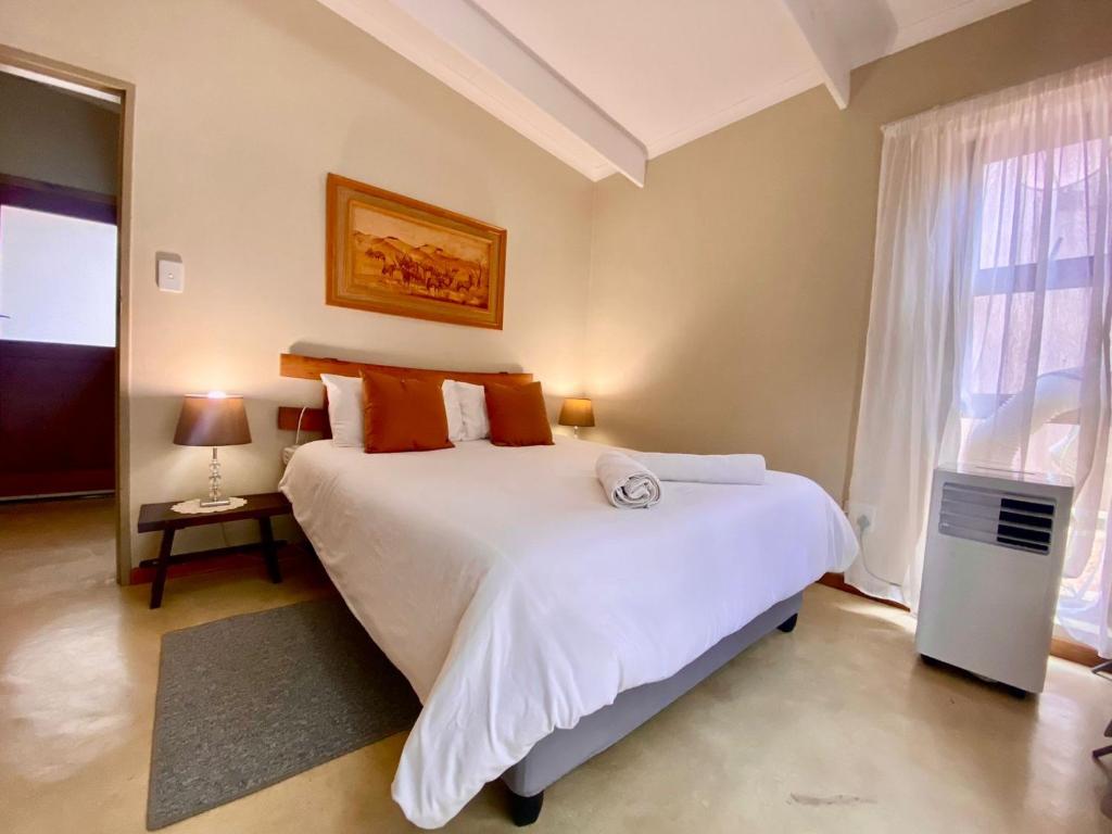 een slaapkamer met een groot wit bed en een raam bij Panache in Hoedspruit
