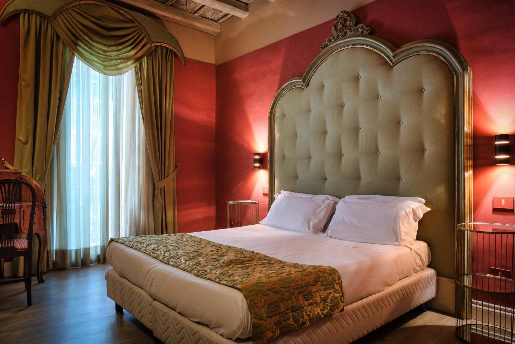 a bedroom with a large bed with red walls at Palazzo Arone dei Baroni di Valentino in Palermo