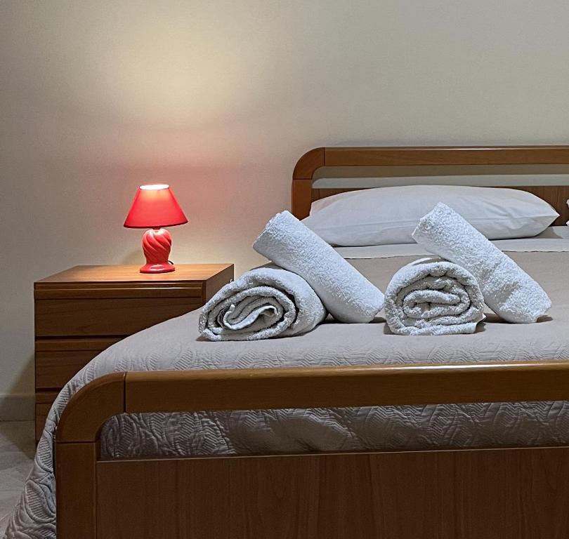 een bed met witte kussens en een rode lamp bij Appartamento A due passi dal mare in Caulonia Marina